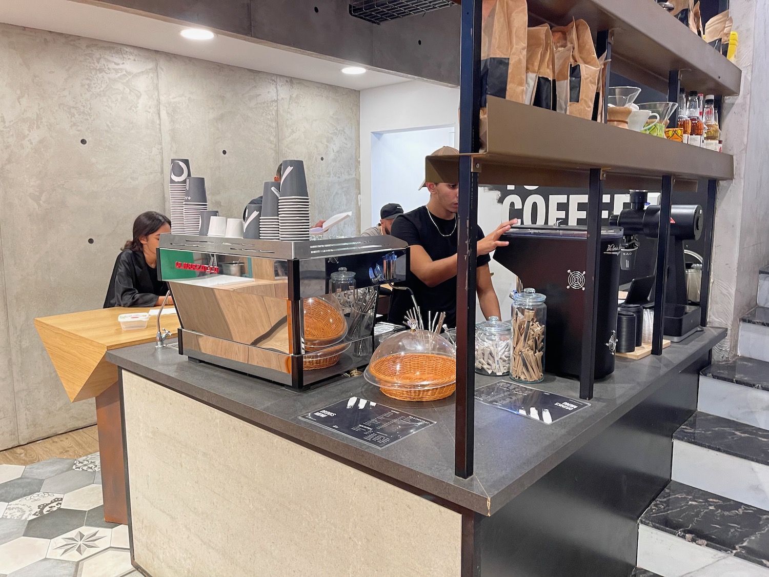 a man standing behind a counter with a coffee machine