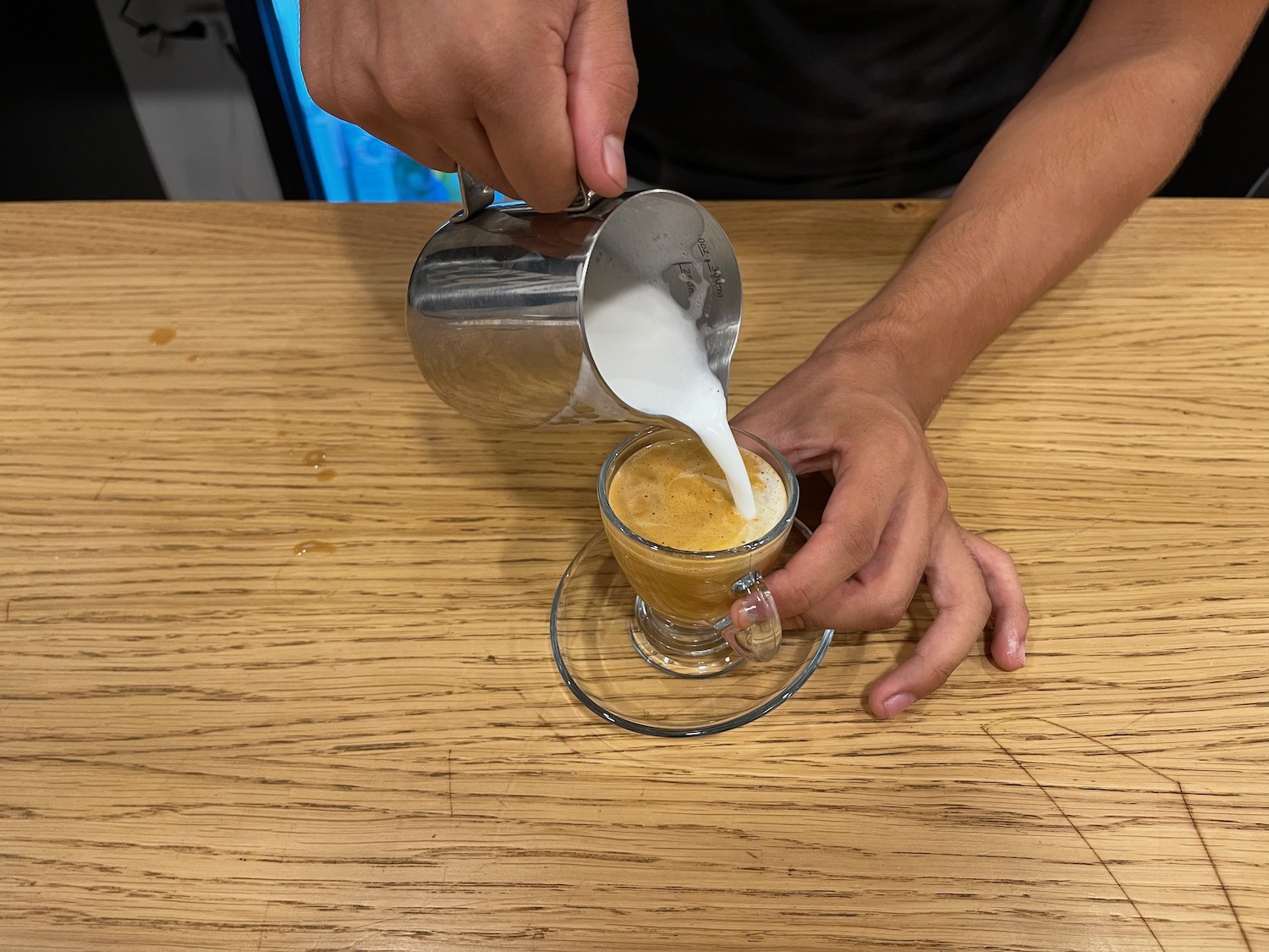 a person pouring milk into a cup of coffee