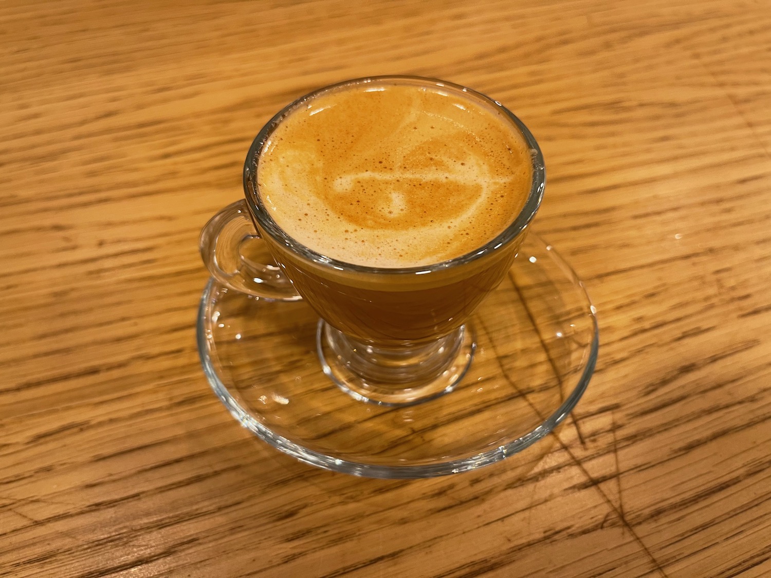 a glass cup of coffee on a saucer