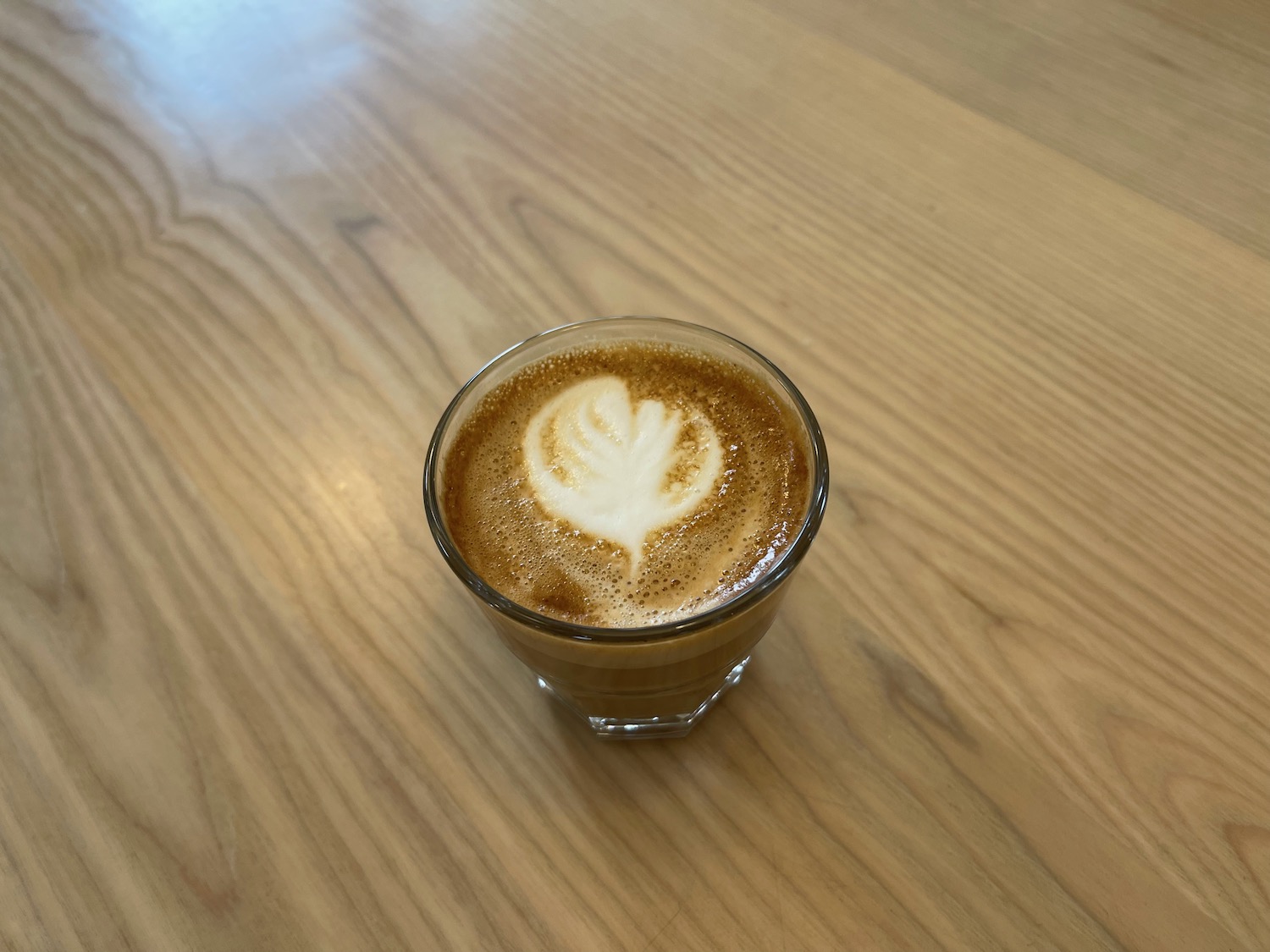 a glass of coffee with a leaf in the foam