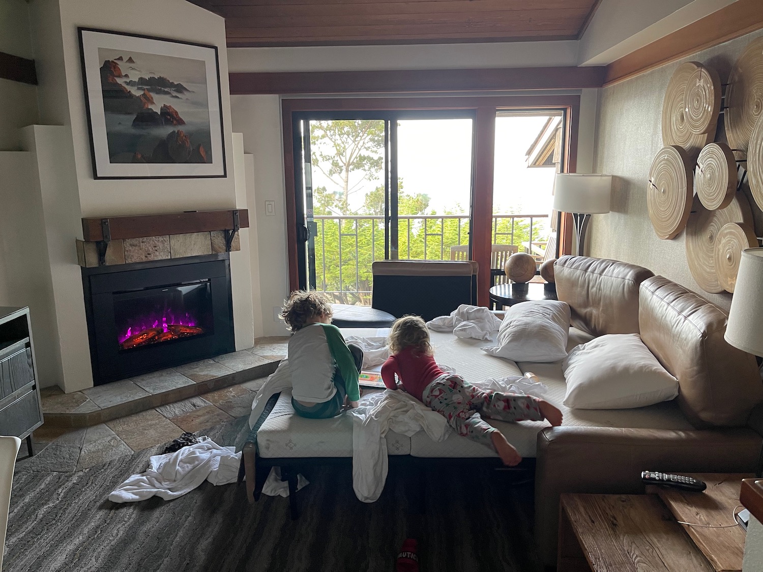 two children sitting on a bed in a room with a fireplace