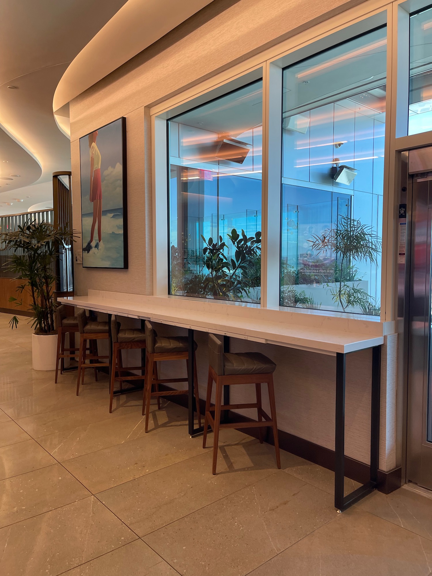 a long table with stools and chairs in front of a glass wall