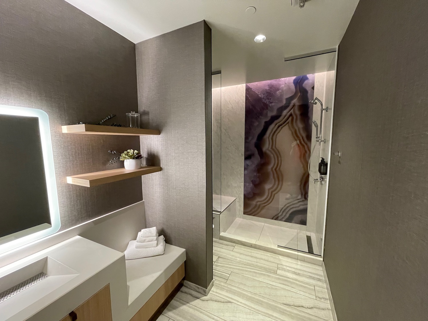 a bathroom with a glass shower and a bench