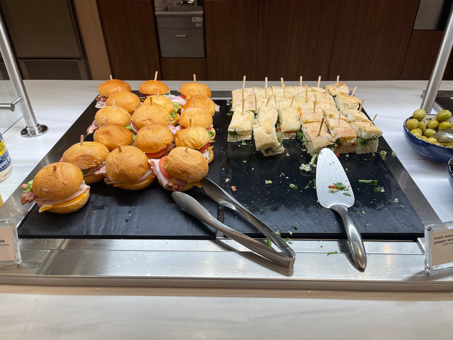 a tray of sandwiches and tongs