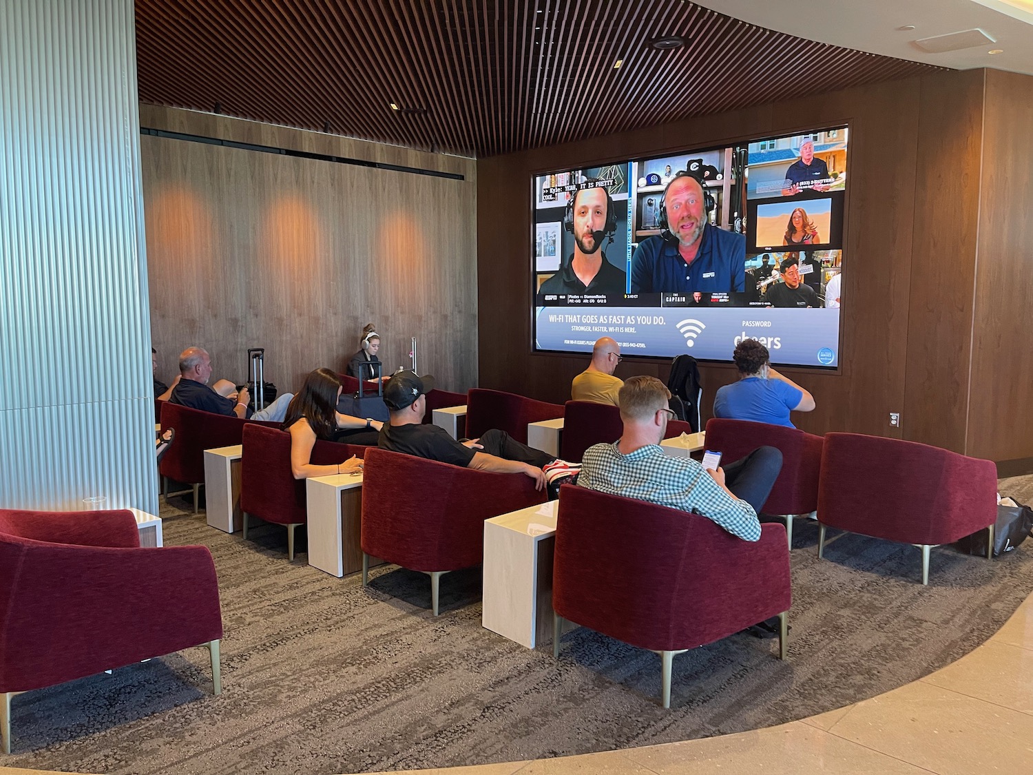 a group of people sitting in chairs in a room with a large screen