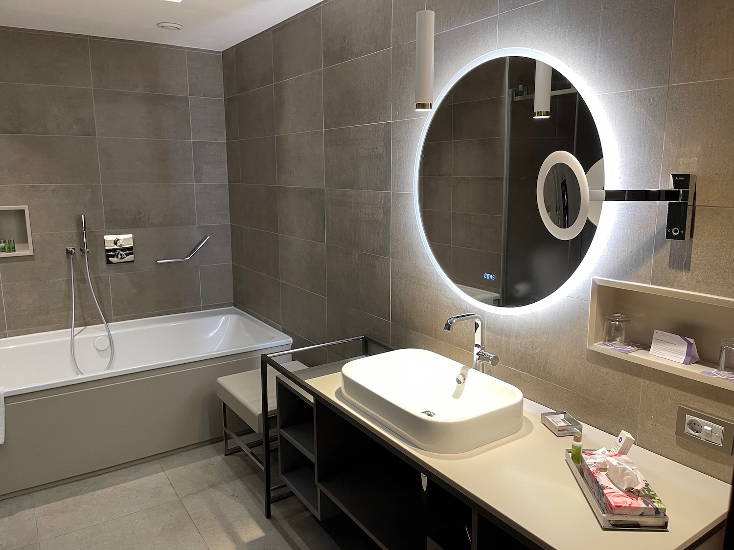 a bathroom with a round mirror and a tub