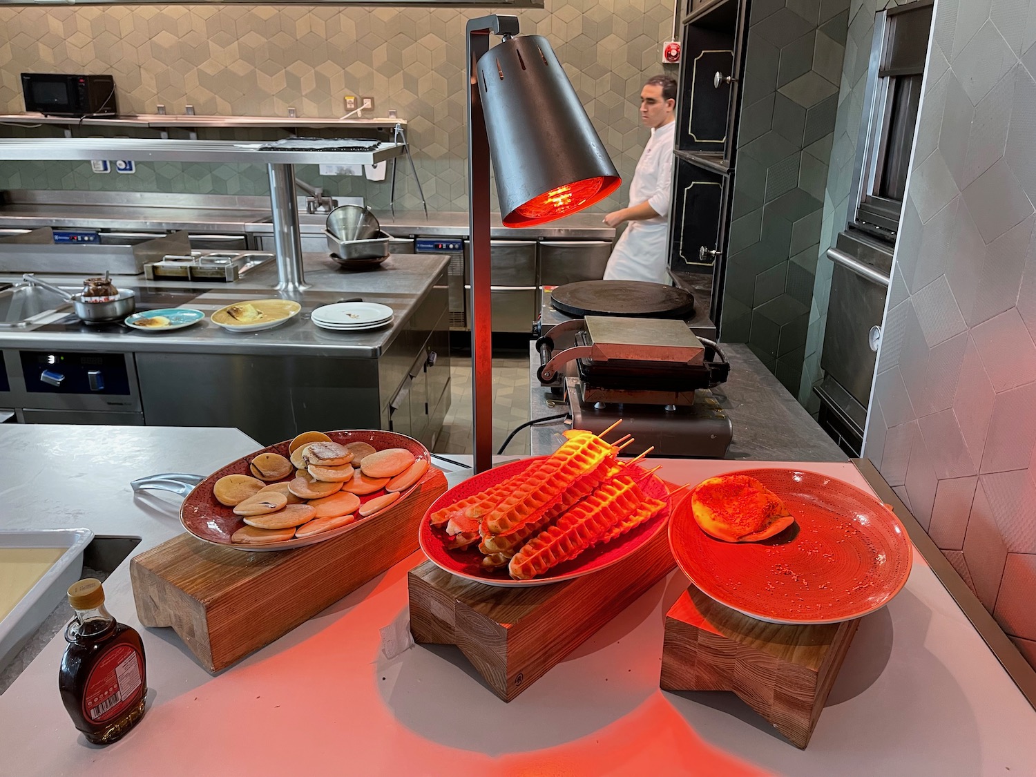 a kitchen with food on skewers and a chef in the background