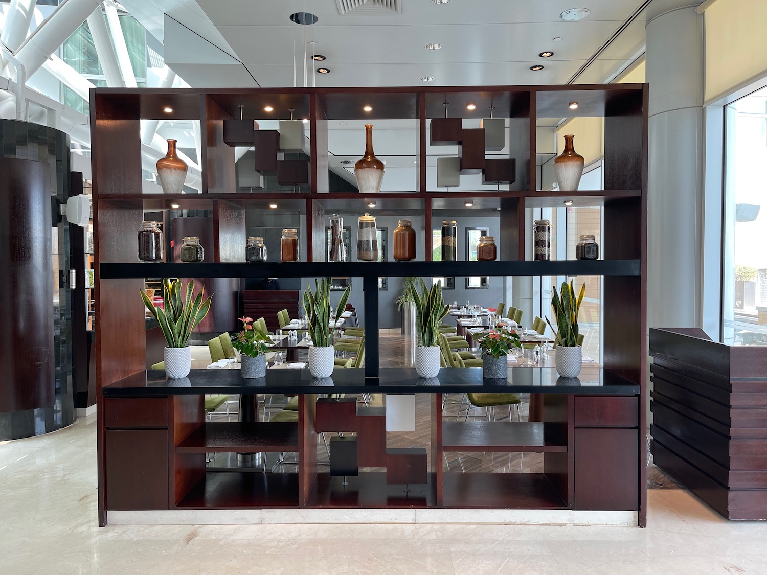 a room with a shelf with plants and a table