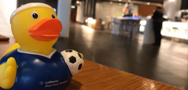 a yellow rubber duck with a football ball on a wooden surface