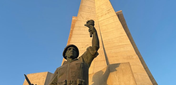 a statue of a man holding a torch and a large tower