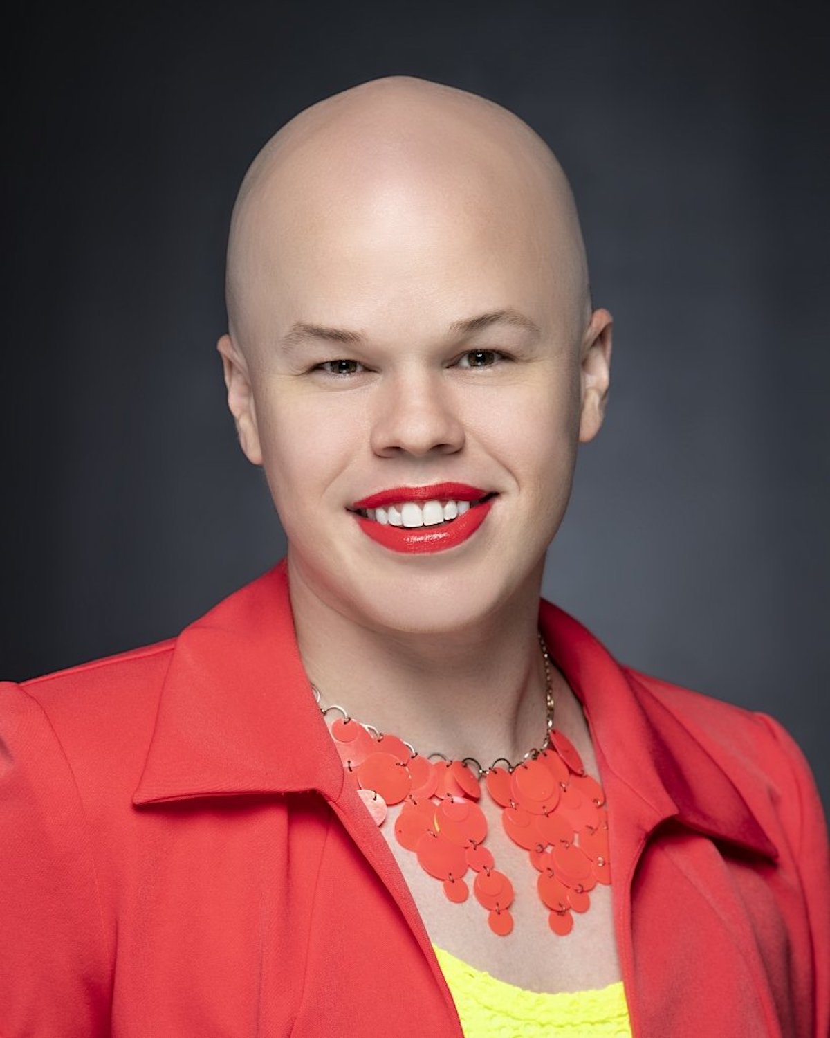 a bald woman wearing a red jacket and red lipstick