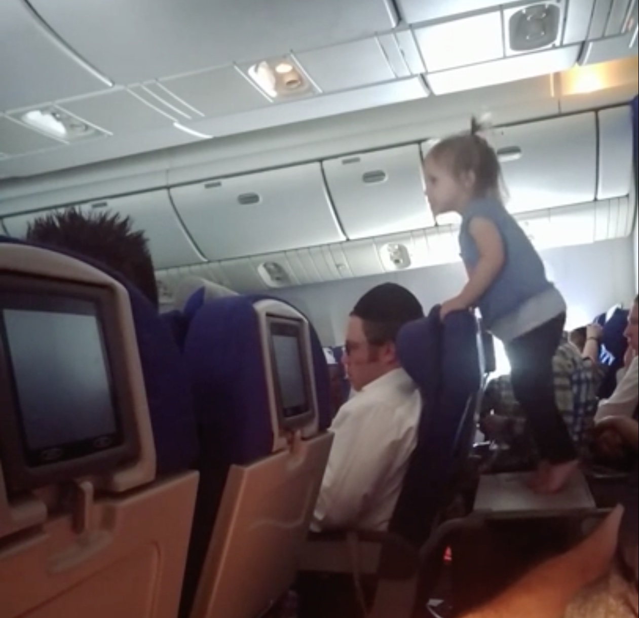 a child climbing on a chair in an airplane