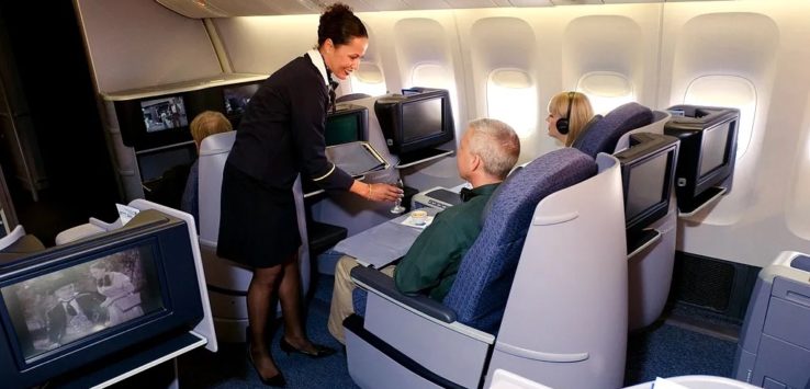 a flight attendant serving a drink to a couple of people