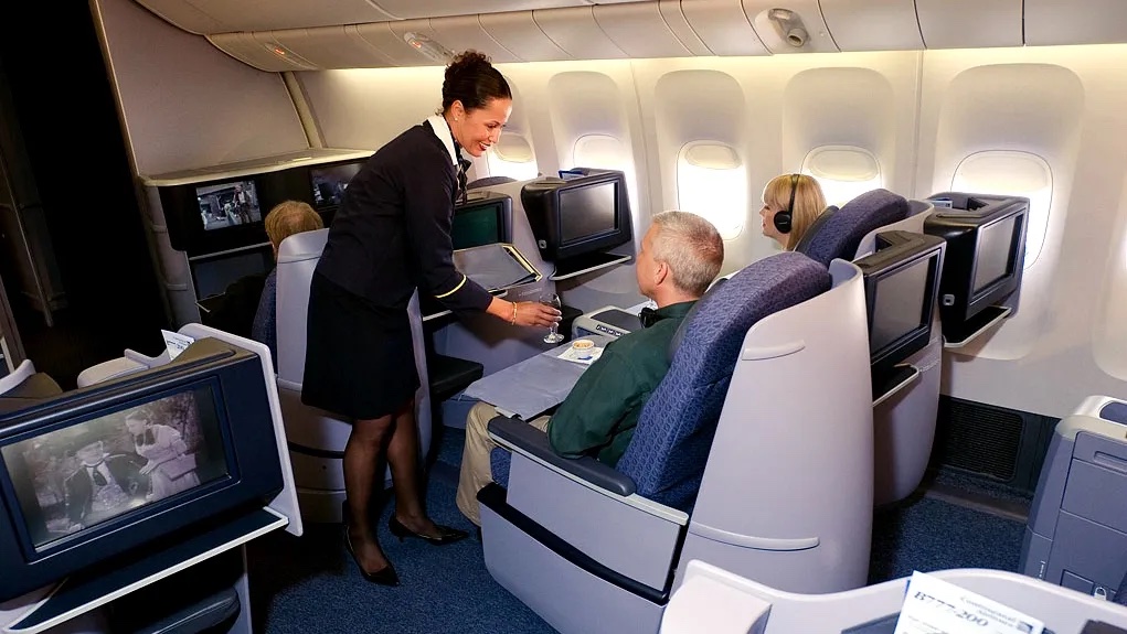 a flight attendant serving a drink to a couple of people