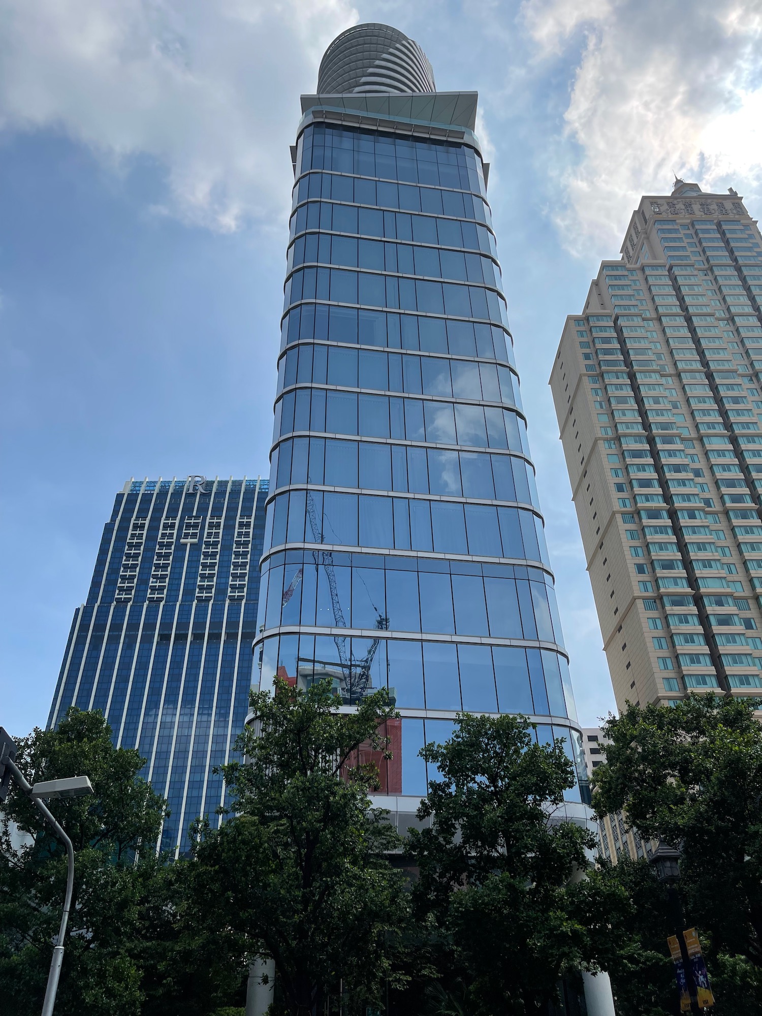 a tall glass building with trees in front of it