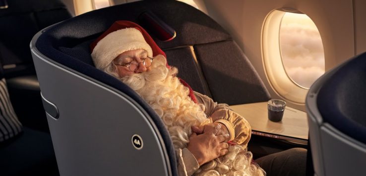 a man in a santa claus garment sleeping in an airplane