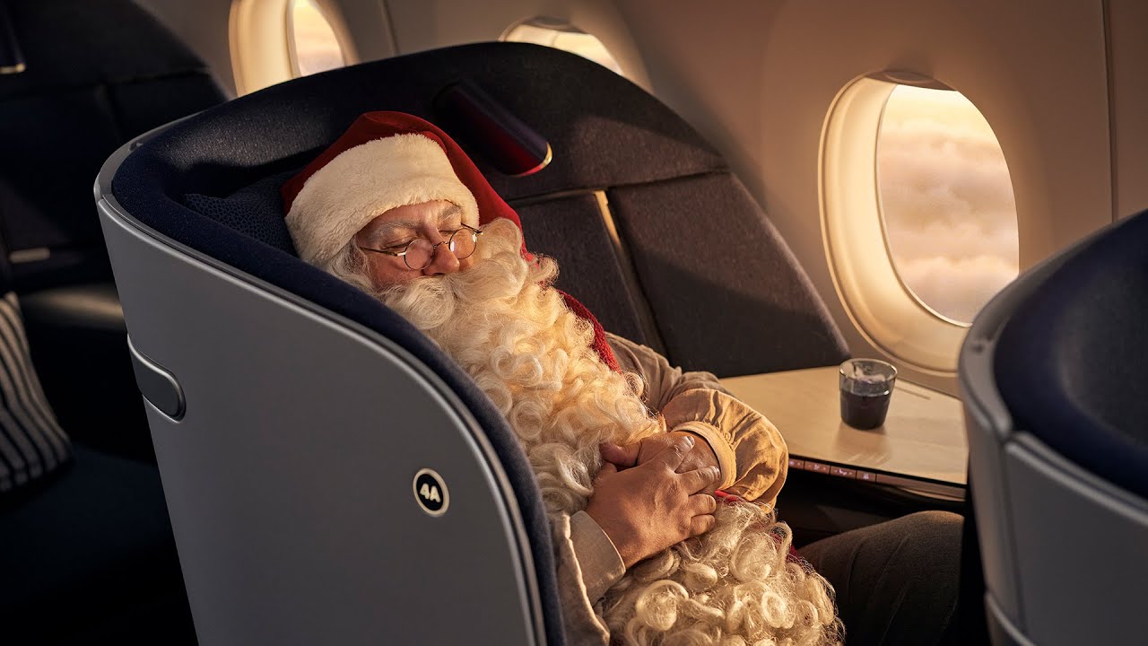 a man in a santa claus garment sleeping in an airplane