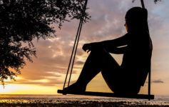 a silhouette of a woman sitting on a swing