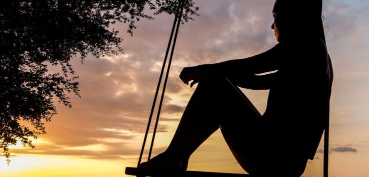 a silhouette of a woman sitting on a swing