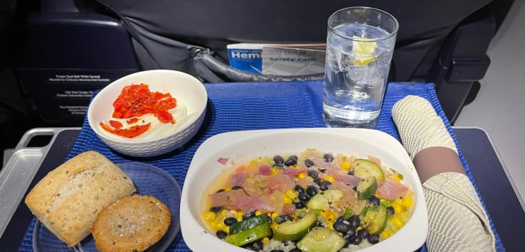 a plate of food and a glass of water on a blue place mat