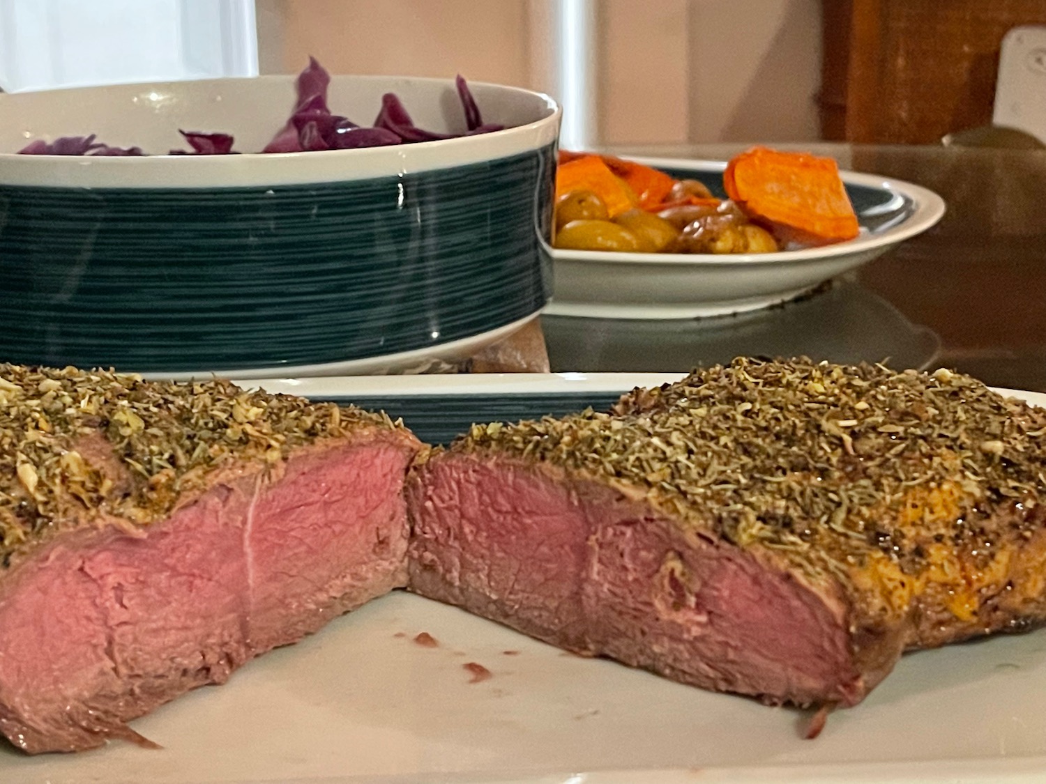 a steak cut in half with a bowl of vegetables in the background