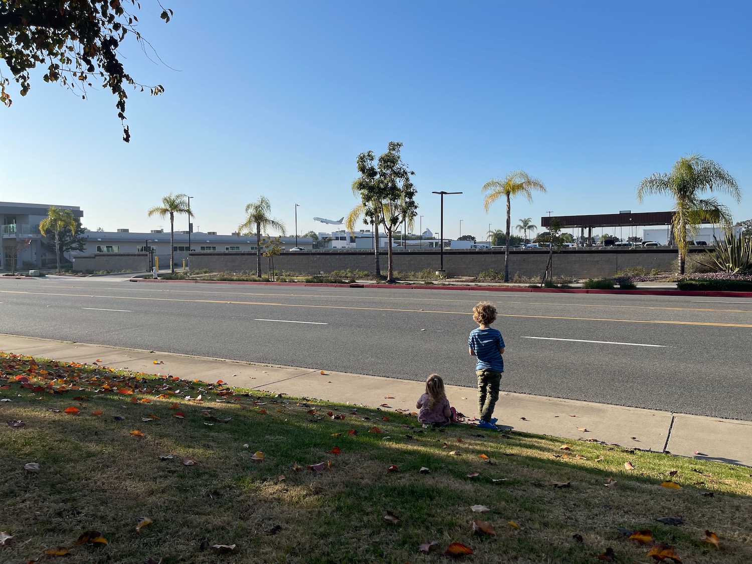 a boy and girl sitting on the side of a road