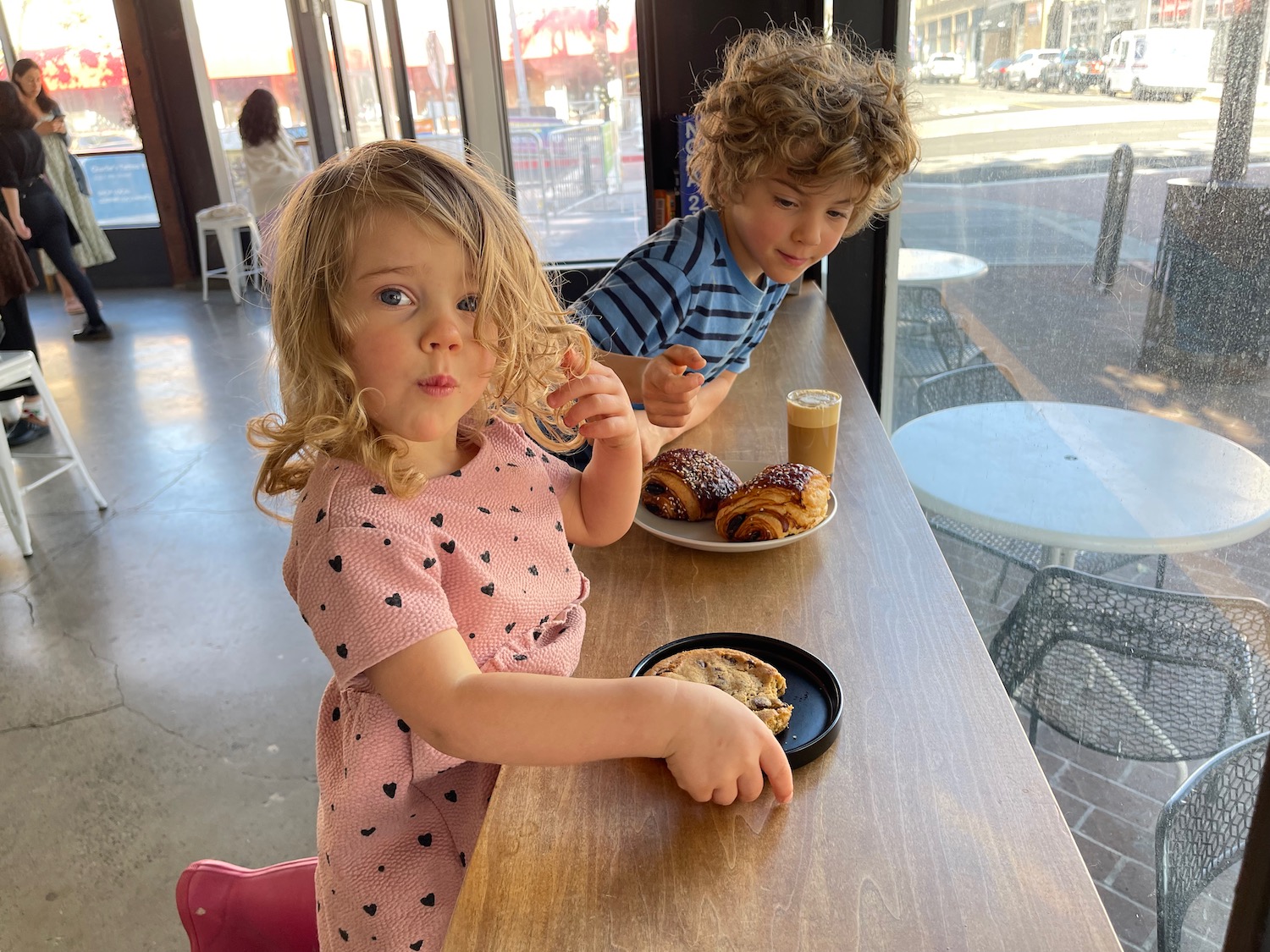 a boy and girl sitting at a table with food