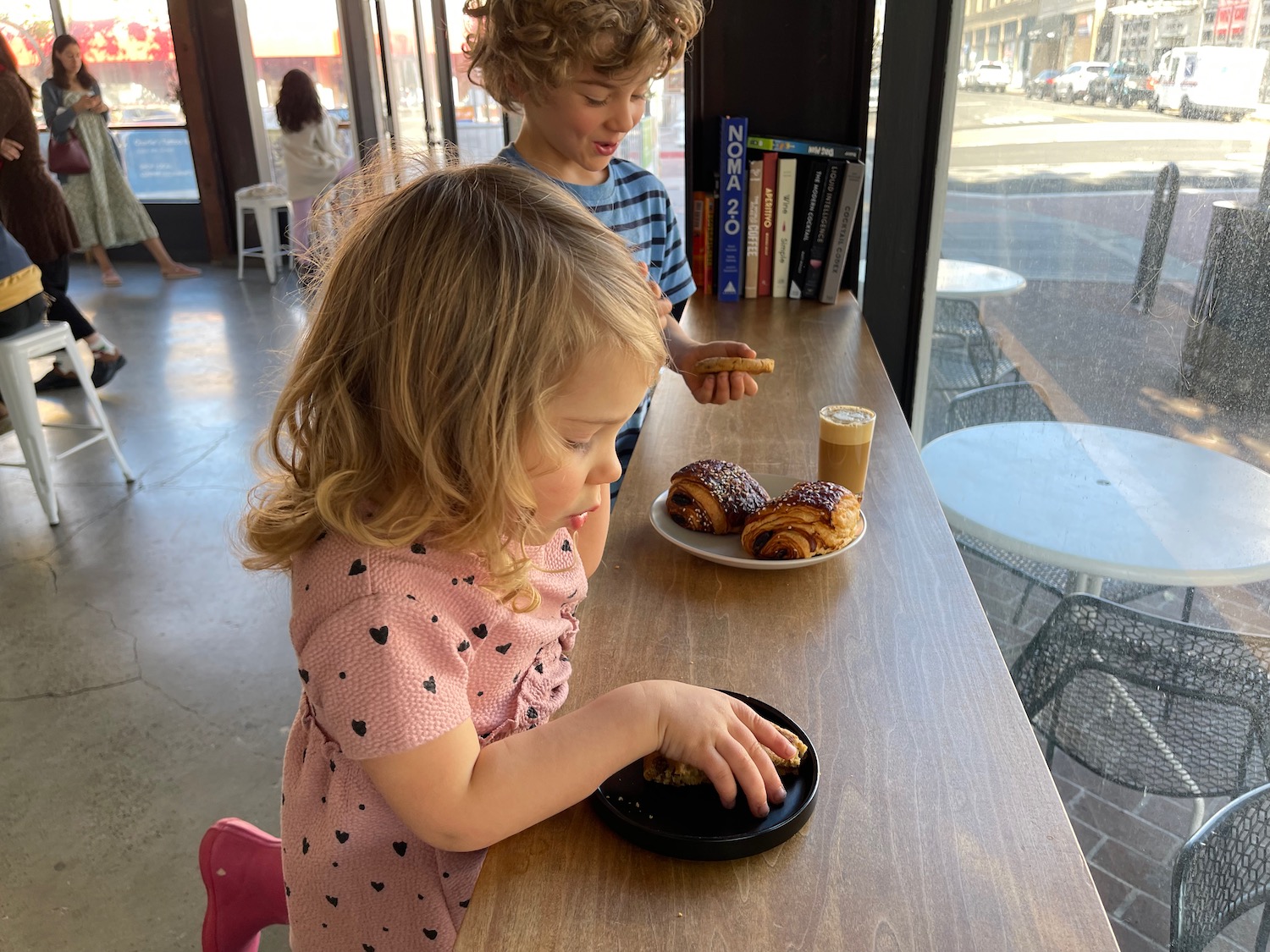 a boy and girl eating pastries at a table