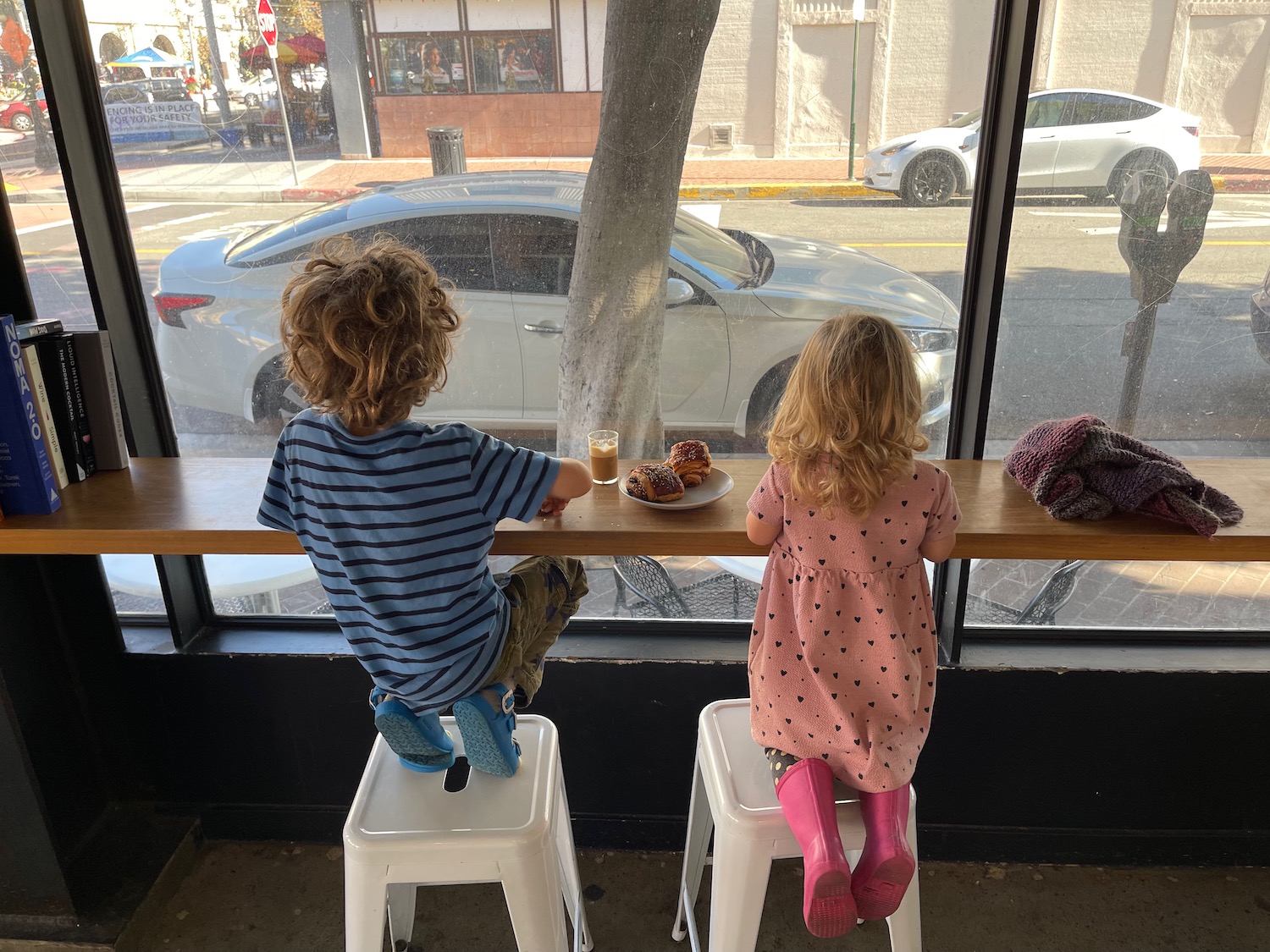 two children sitting at a table looking out a window