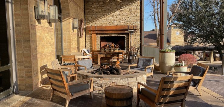 a patio with a fire pit and chairs