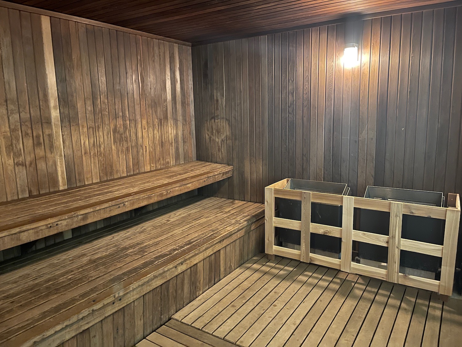 a wooden sauna with a wood bench and trash can