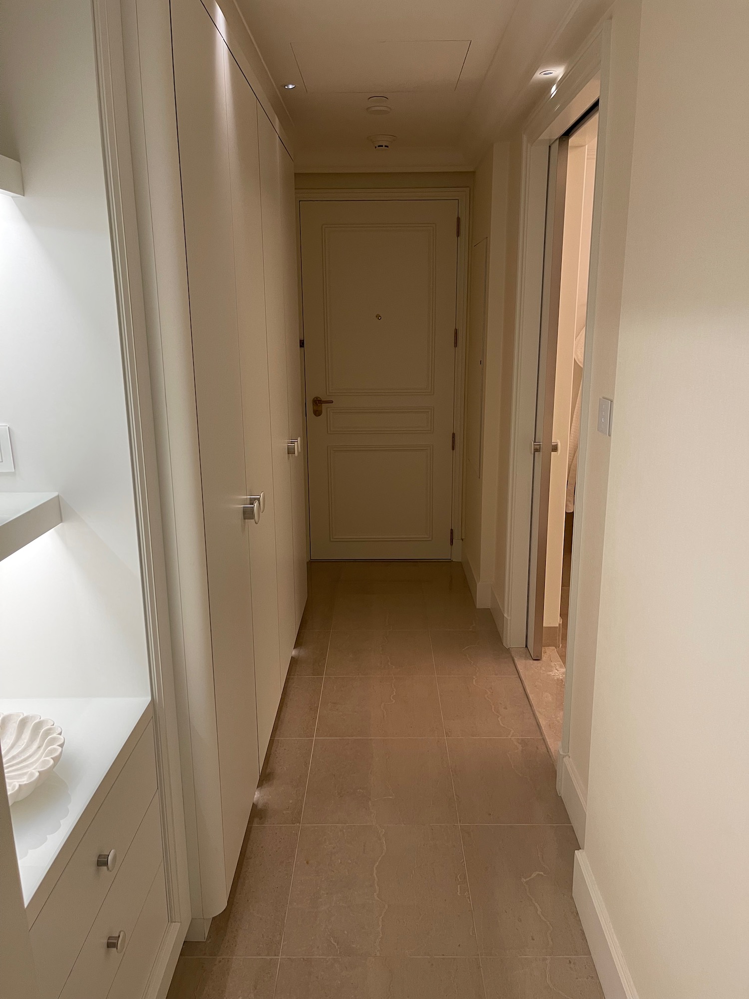 a hallway with white doors and a white shelf
