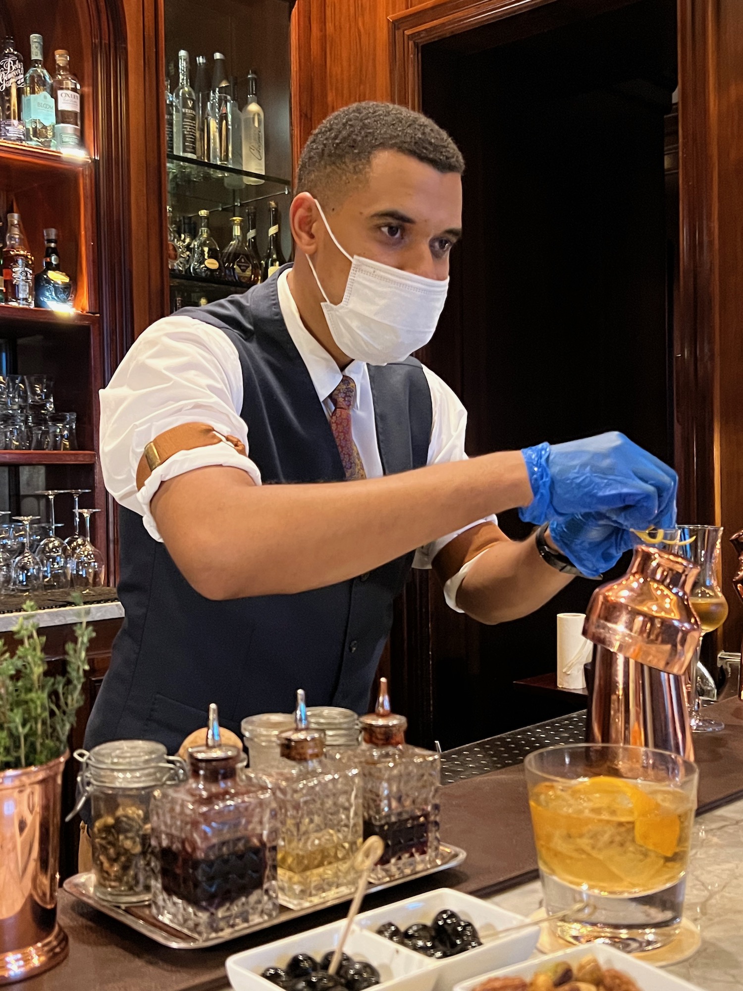 a man wearing a mask and gloves making a drink