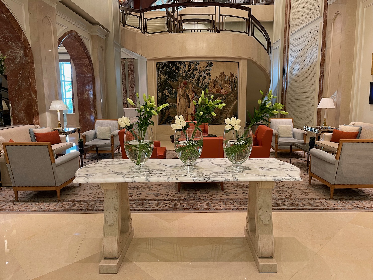 a marble table with vases of flowers in front of a large painting