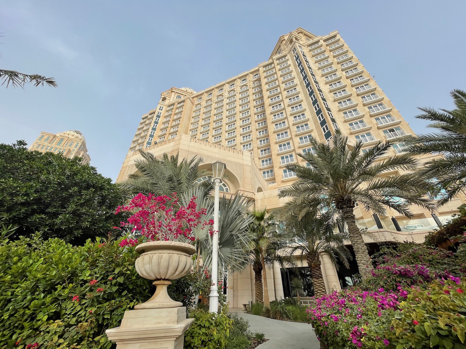 a tall building with palm trees and flowers