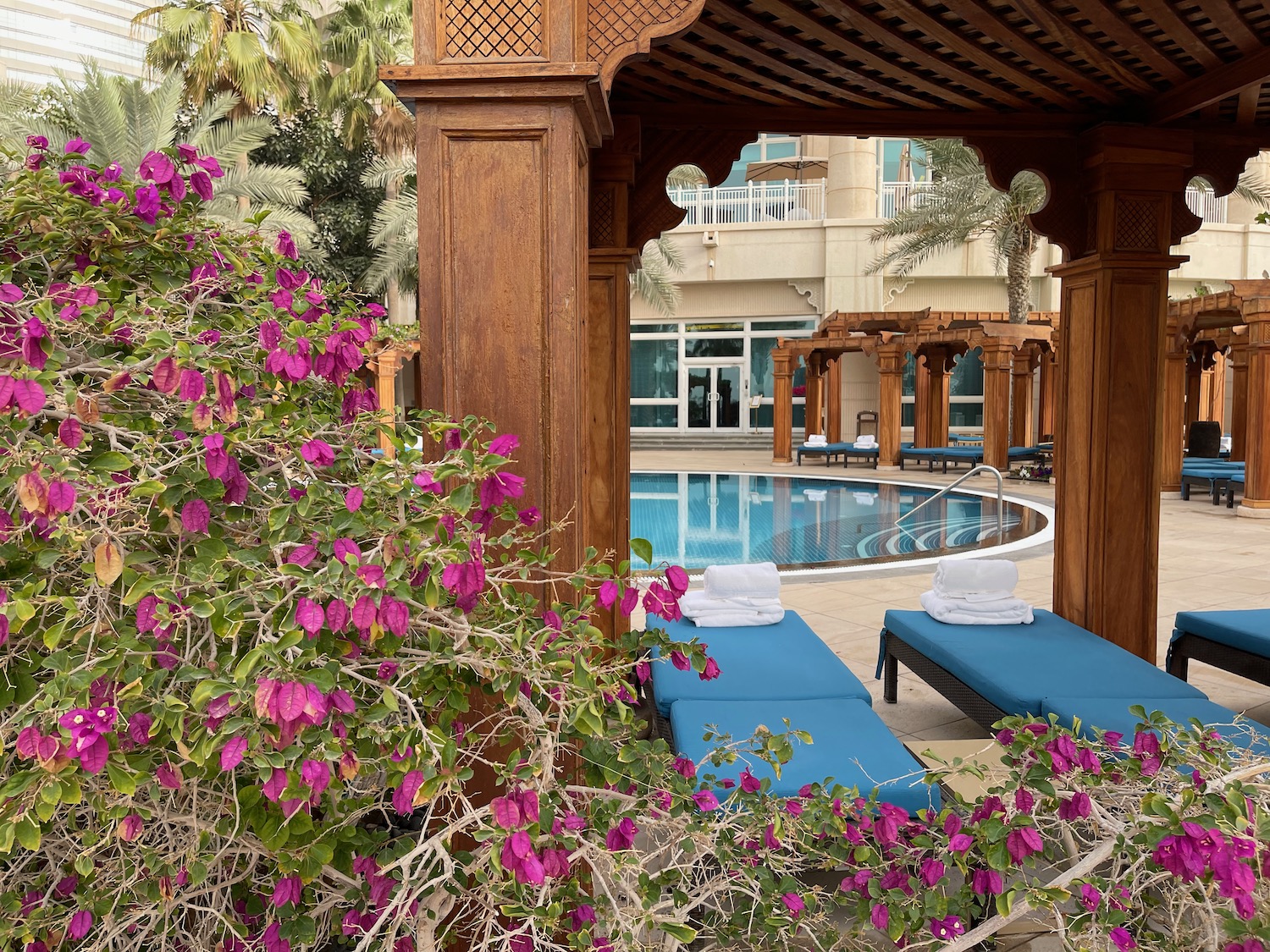 a pool with lounge chairs and purple flowers