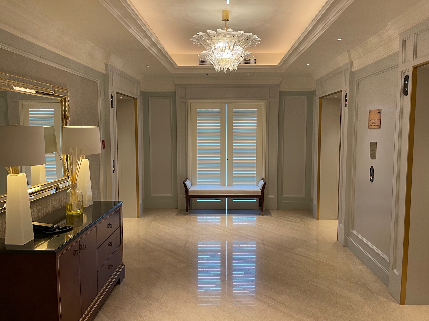 a hallway with a chandelier and a mirror