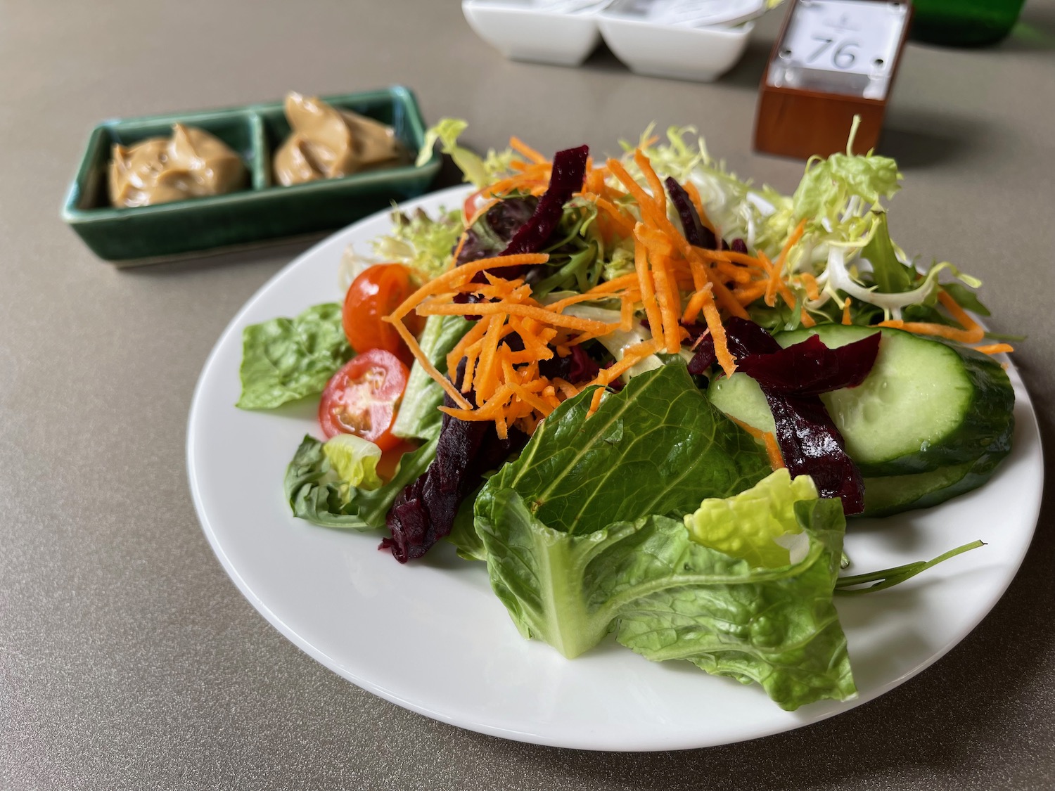 a plate of salad with a small bowl of sauce