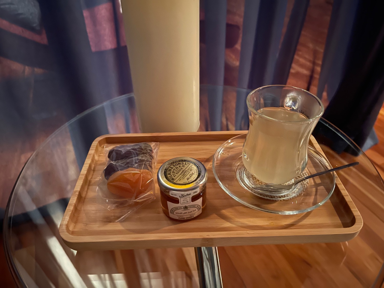 a tray with a glass of liquid and a jar of jam on it