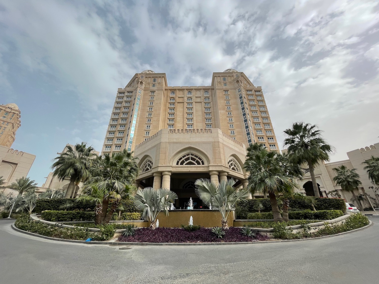 a large building with a fountain and palm trees