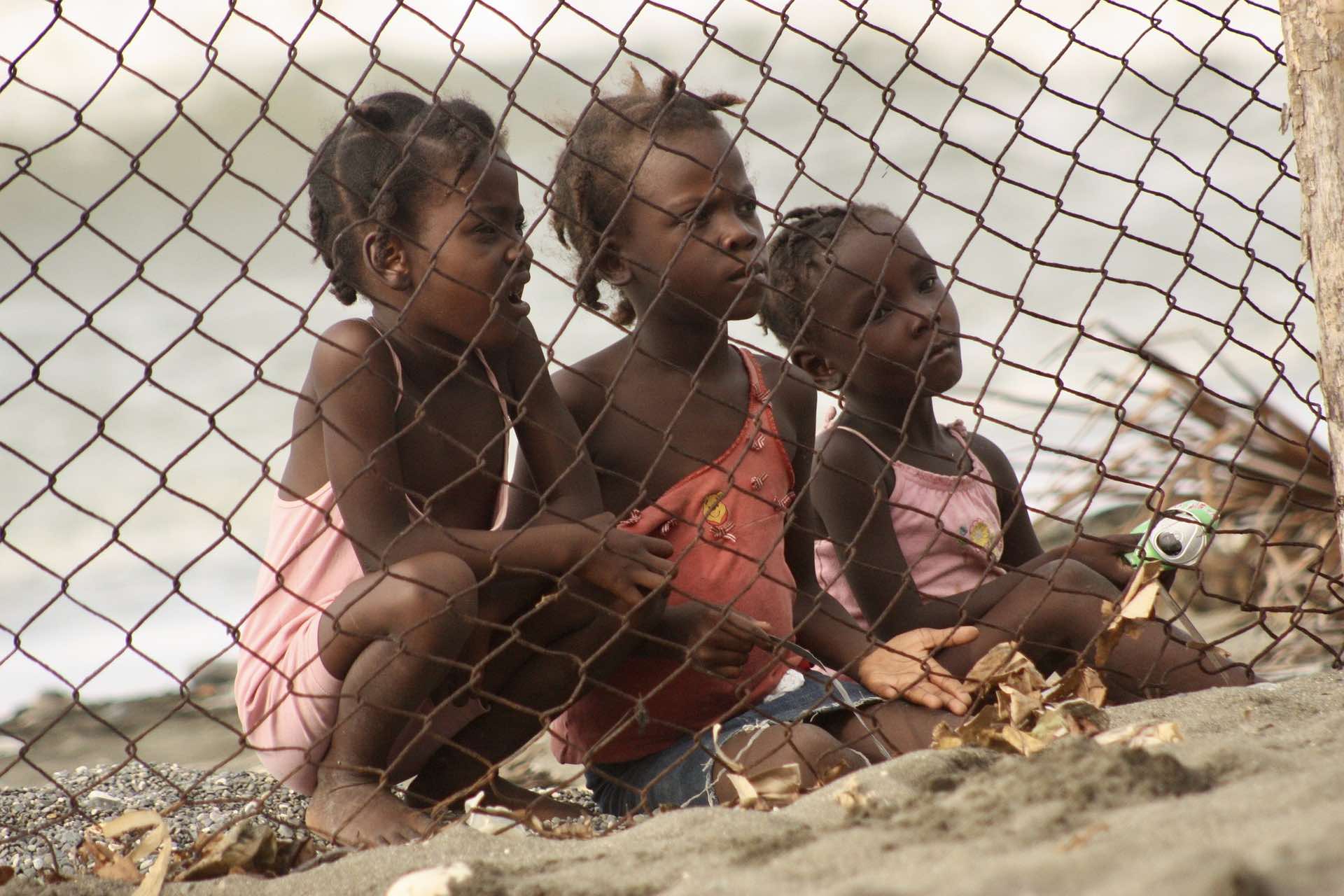a group of children sitting behind a fence