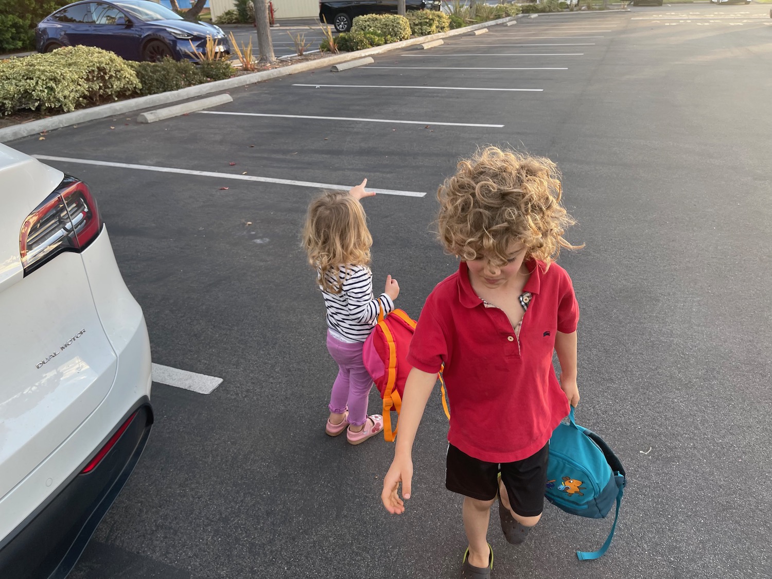a boy and girl walking in a parking lot