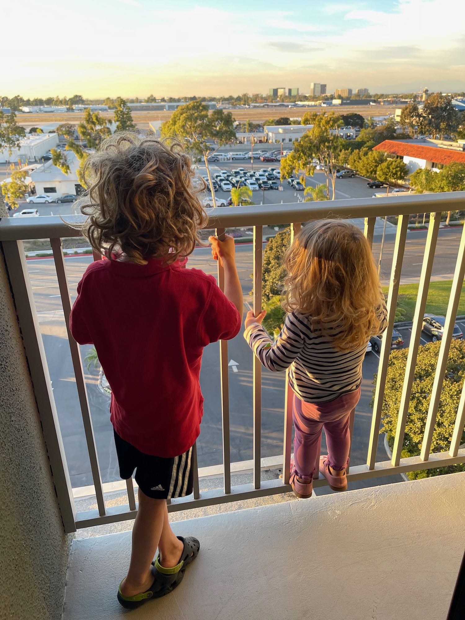 two children standing on a balcony looking at a city