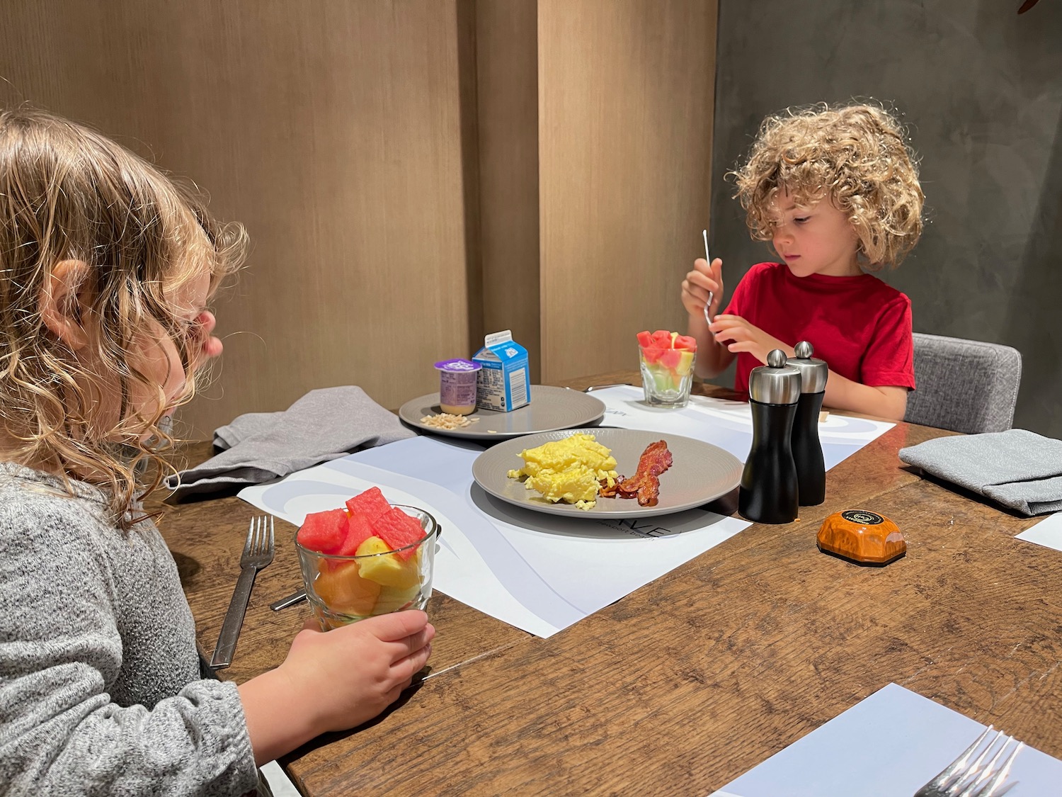 a couple of children sitting at a table eating food