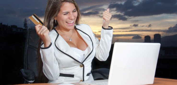 a woman holding a credit card and looking at a laptop