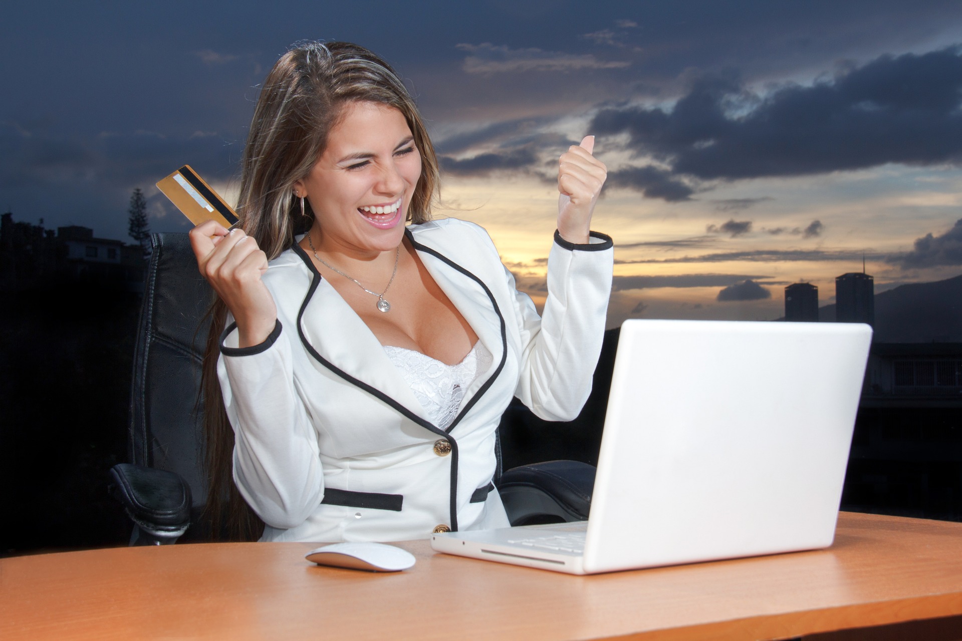 a woman holding a credit card and looking at a laptop