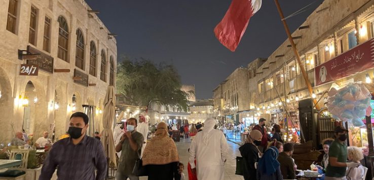 a crowd of people walking on a street with a flag