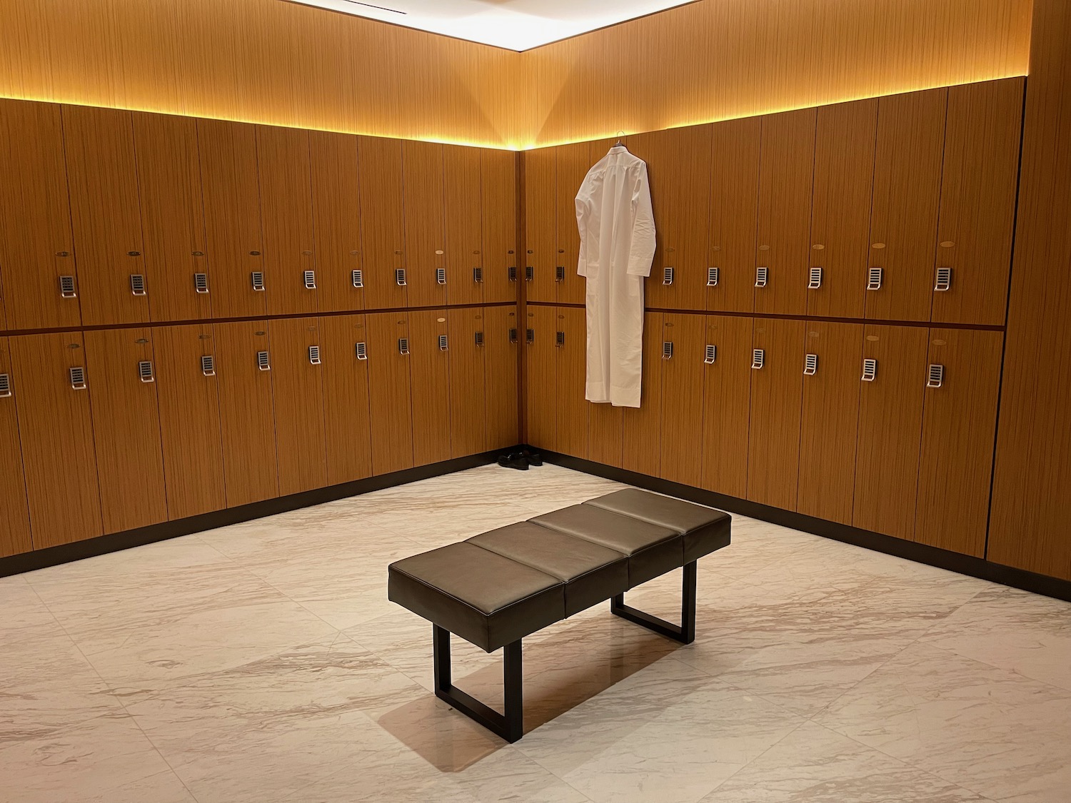 a room with a bench and a white robe on the wall