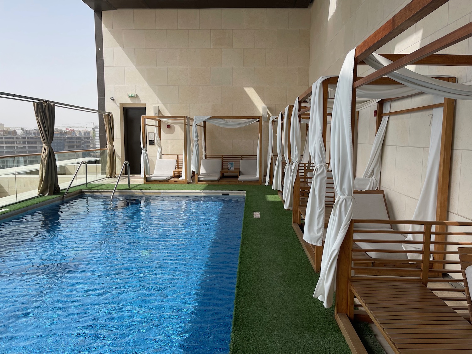 a pool with white canopy beds and a green carpet