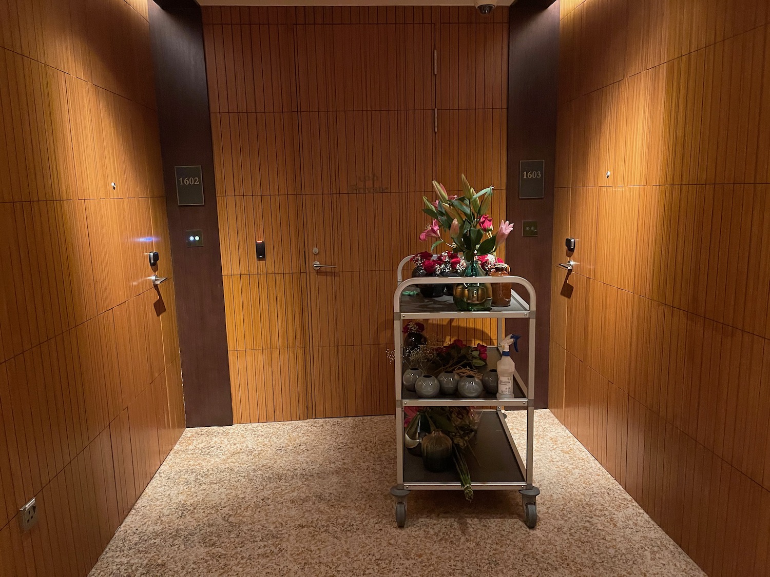 a cart with flowers and vases in a room with doors